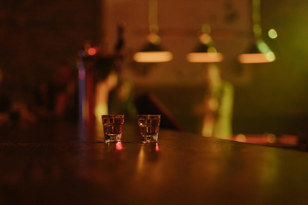 Two tequila shots on a dimly lit bar counter, creating a warm, inviting atmosphere in a bar setting.
