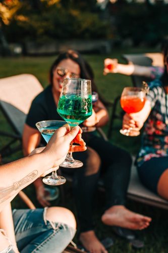 Group of friends enjoying drinks and companionship outdoors in summer.